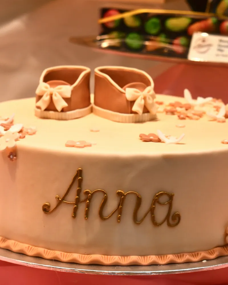 Tort de botez cu pantofiori de zahăr și numele copilului scris pe el
